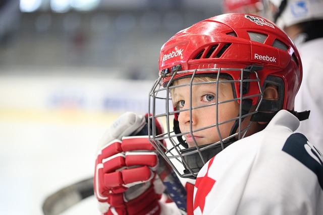 A young hockey player sits on the bench during a game, highlighting the important of using a mouth guard for dental protection.