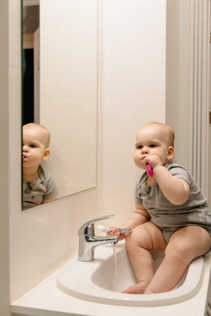 pexels photo 7491458 7491458 Adorable baby brushing teeth in bathroom sink, showcasing early oral hygiene habits.