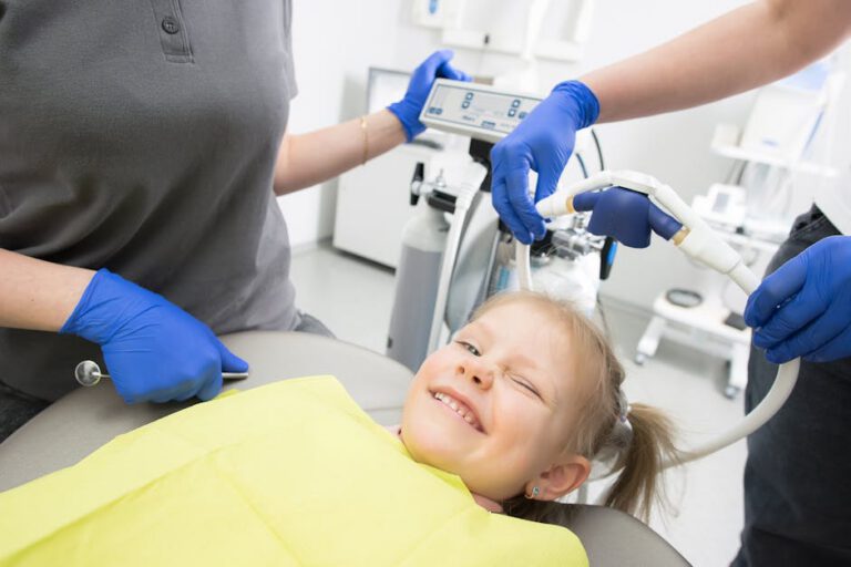 A cheerful child winks while sitting in a dental chair, surrounded by dental professionals at the family-friendly Horizon Dental Kamloops